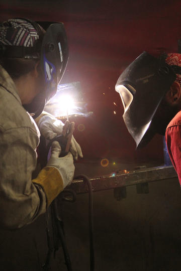 Instructor Closely Observing a Student Welding