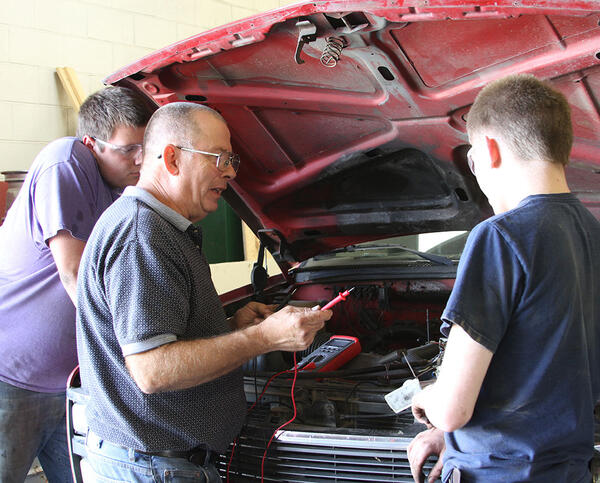 Instructor Roy Shafer Showing Two Students a Diagnostic Technique Under the Hood of a Pick-up