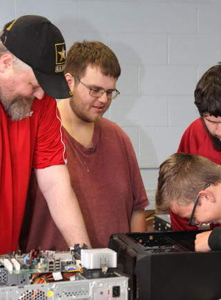 Group of Students Working on a PC with Instructor Providing Guidance