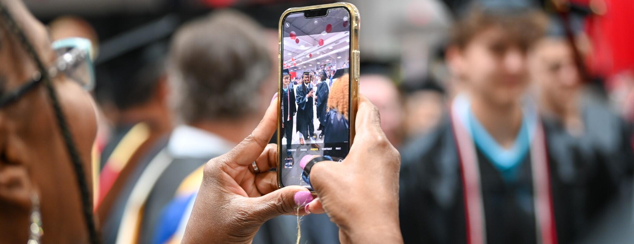 Parent Taking a Photo with her Phone at Graduation