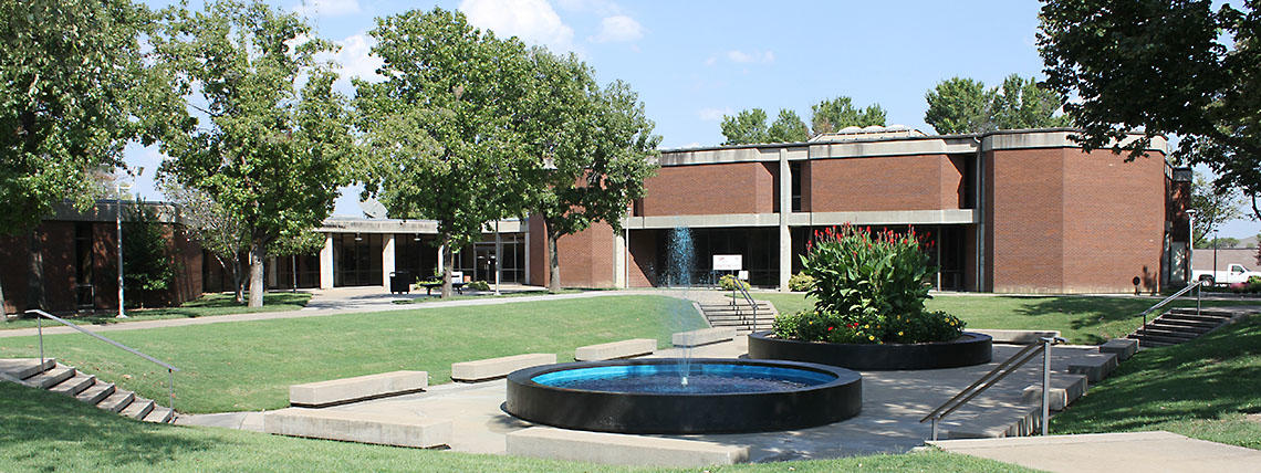 Wide View of Campus Courtyard With Full Foliage and Fountain Running