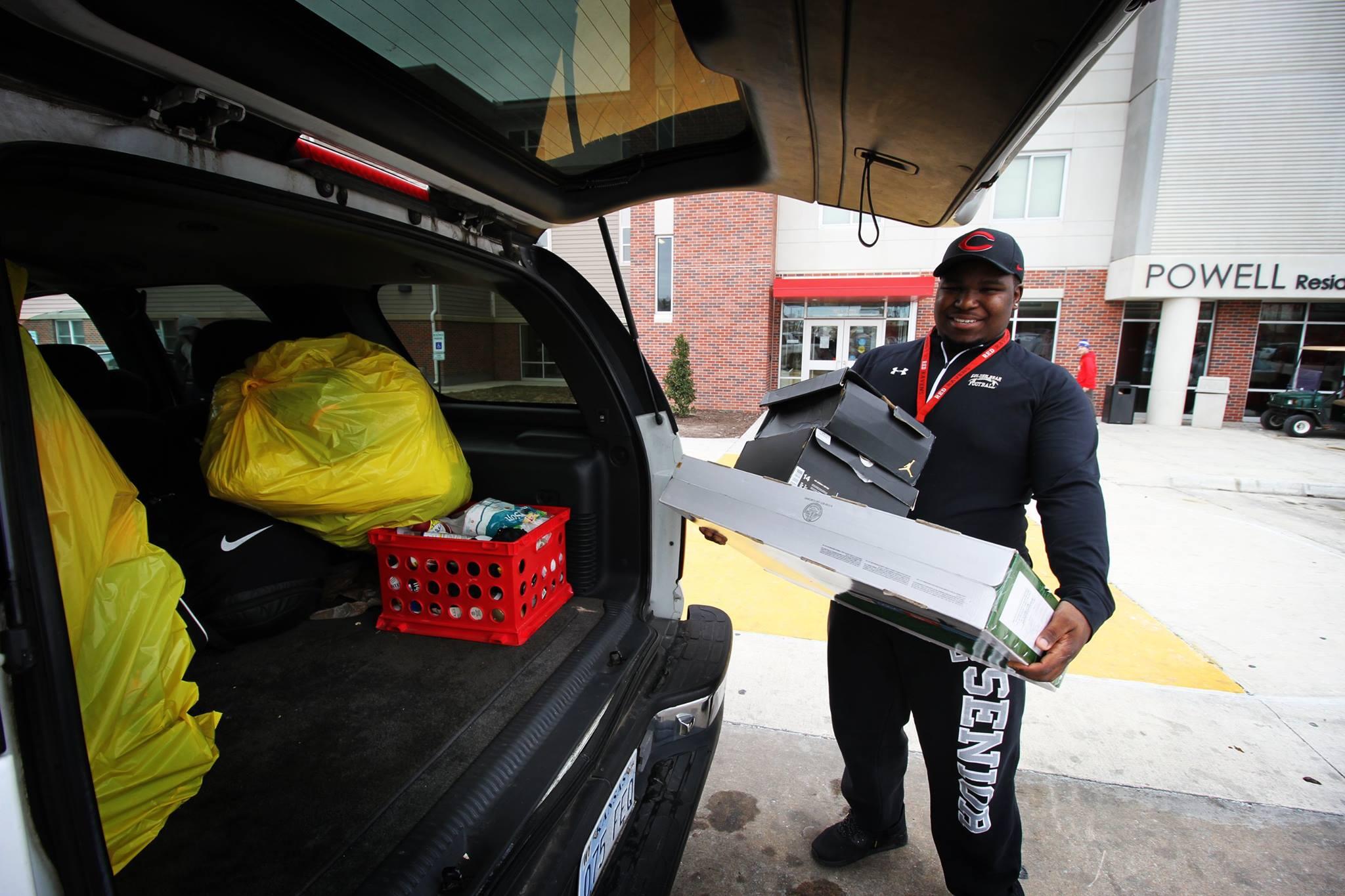 Student unloading a large flat box from the trunk of his car on move-in day